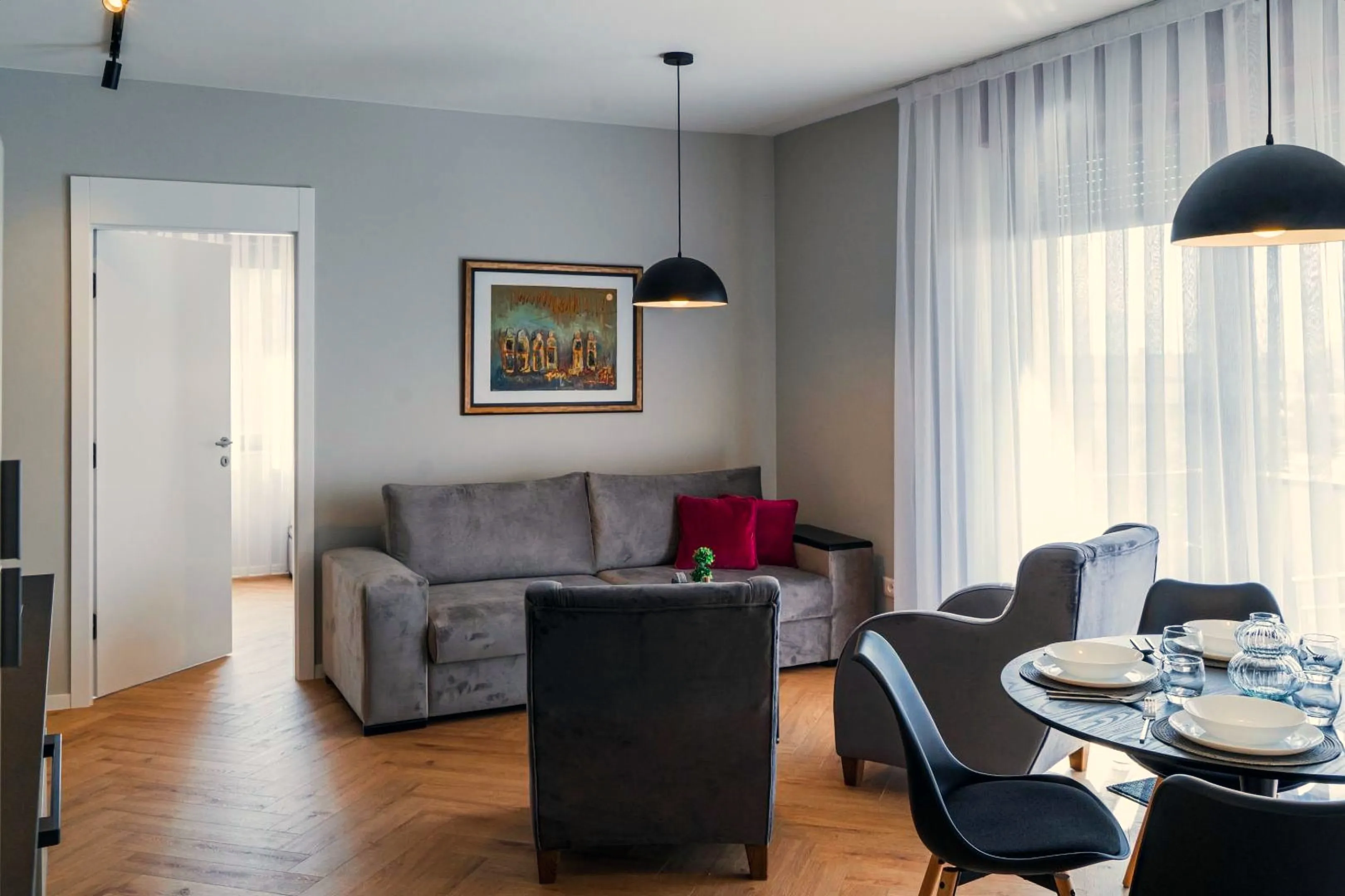 The grey sofa bed with two burgundy cushions under a framed painting in the living room